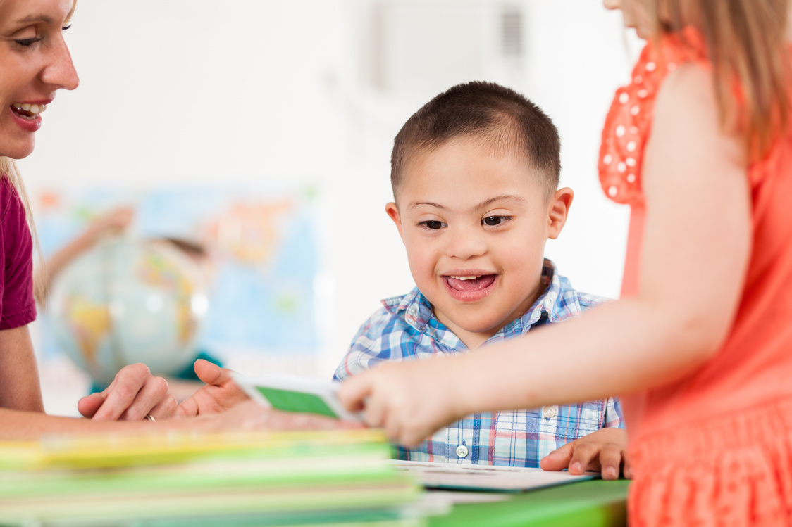 Excited little boy with down syndrome plays in preschool class