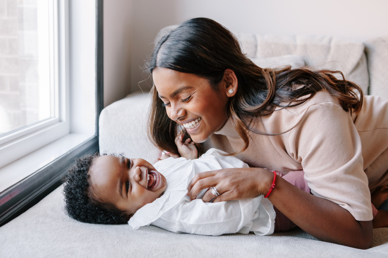 Mother Tickling Her Baby on the Bed